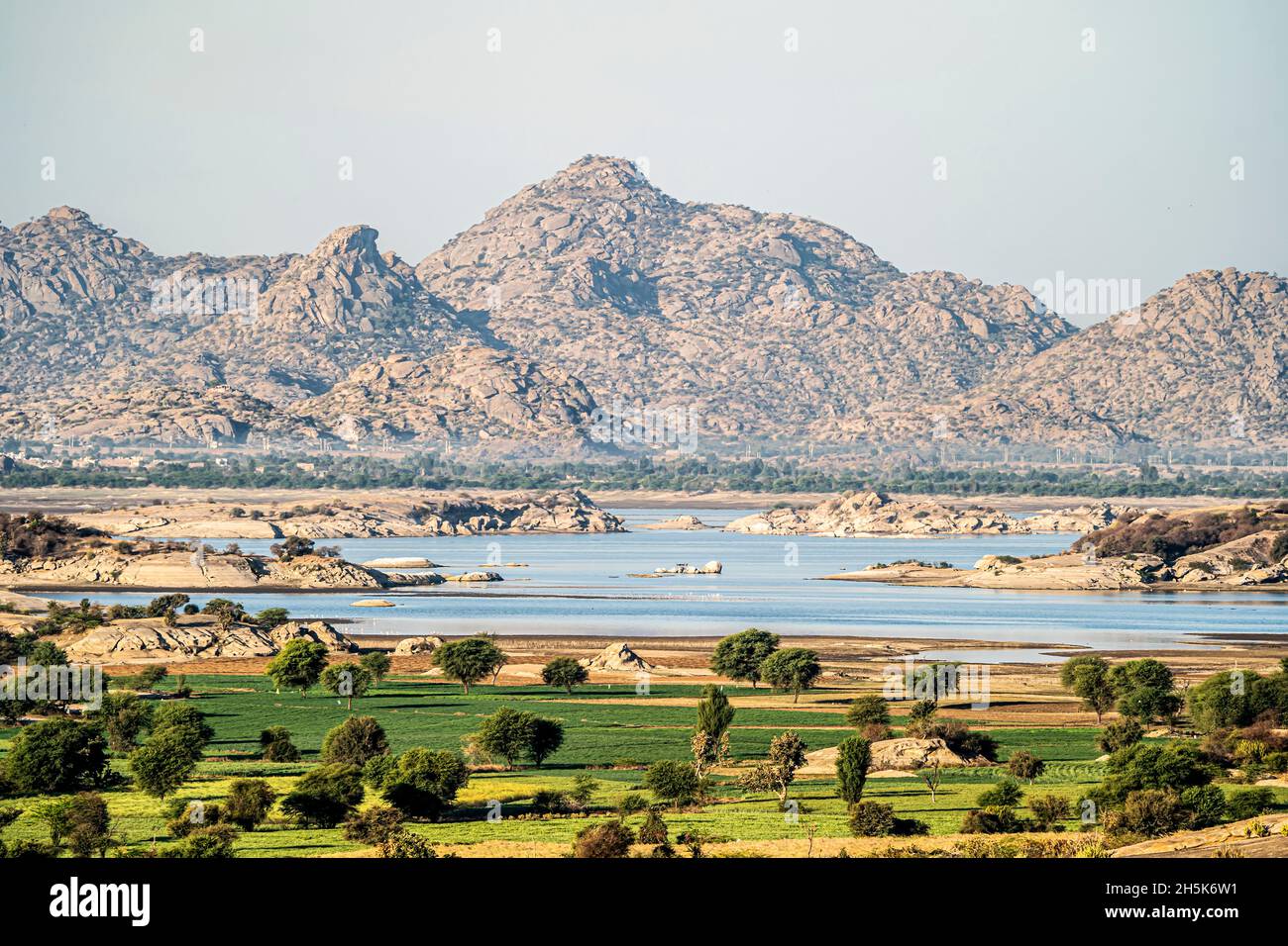 El paisaje de un lago de presa y el desierto con las colinas rocosas de Aravali en la llanura de Pali de Rajasthan; Rajasthan, India Foto de stock