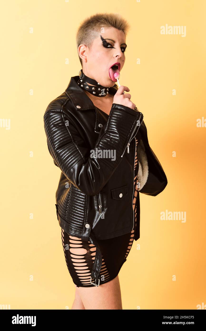 Pelo corto rubio rock chica lamer un lollypop con una chaqueta de cuero y  un vestido con agujeros Fotografía de stock - Alamy