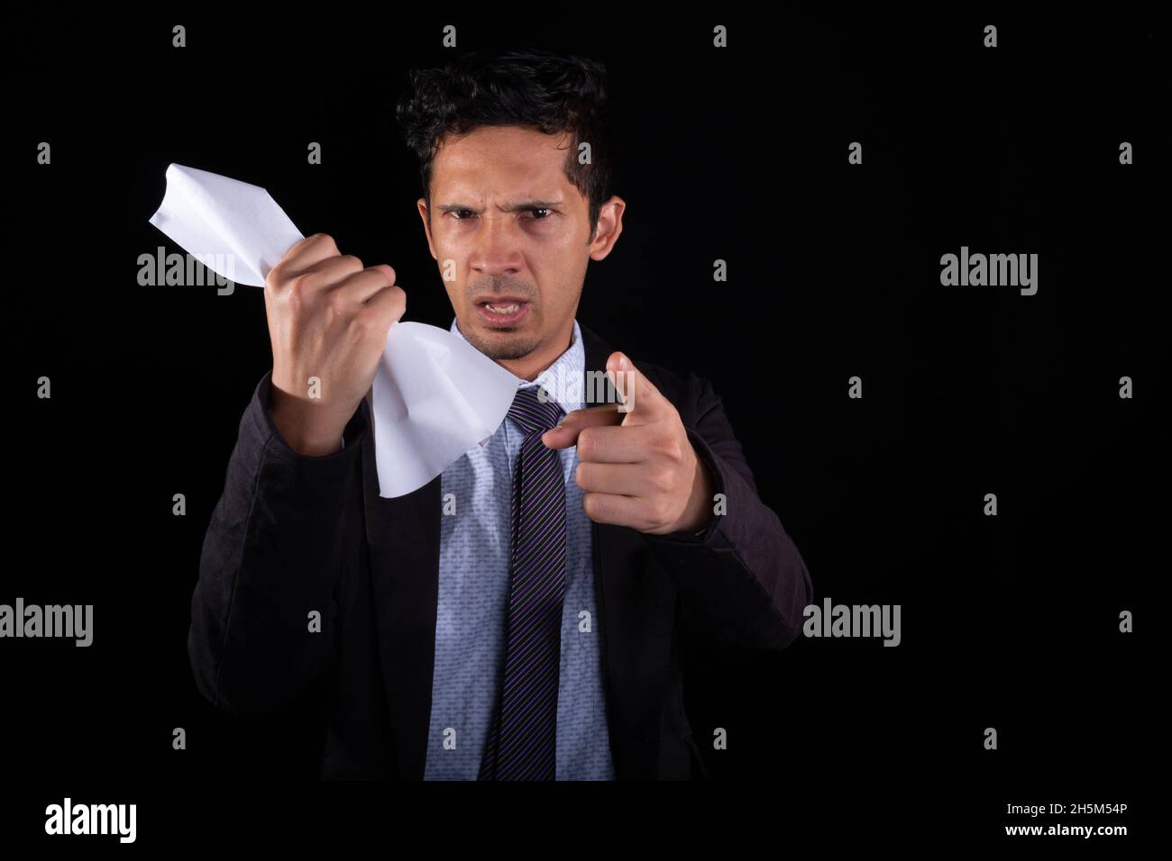 Hombre de negocios enojado apuntando hacia adelante mientras sostiene un pedazo de papel en su mano. Empresario que se regala por mala gestión del contrato. Foto de stock