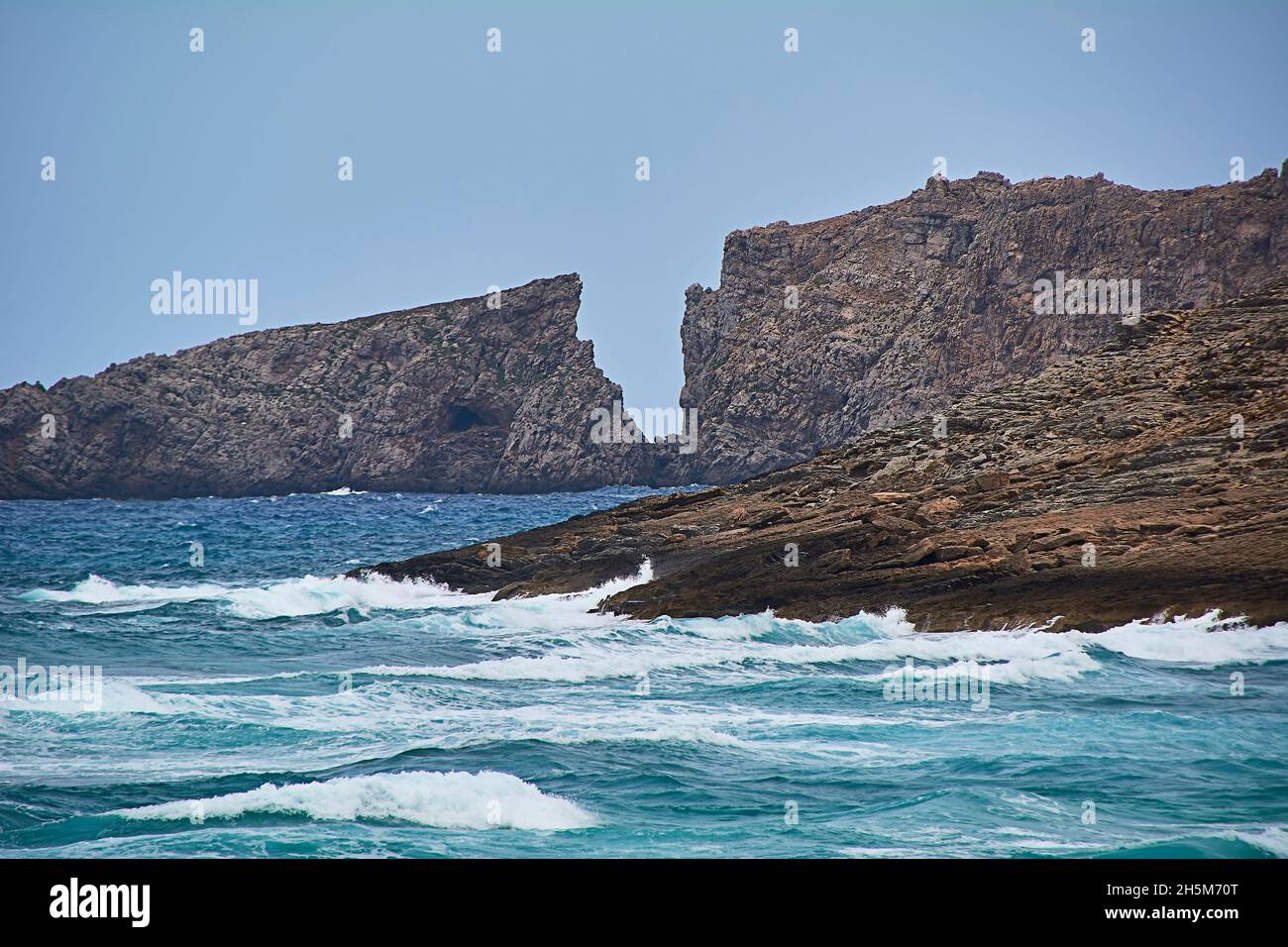 Acantilado en la costa en forma de carta frente al Mar Mediterráneo, Islas Baleares, aguas turquesas, aguas en movimiento Foto de stock