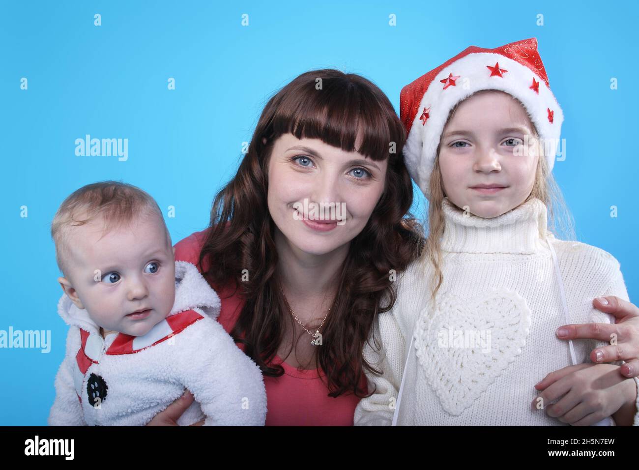 Madre joven con dos niños con gorras navideñas Foto de stock