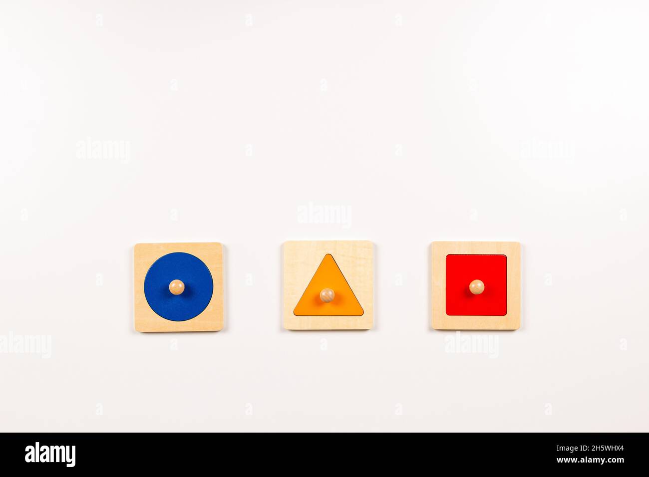 Colorido material sensorial Montessori de madera que aprende juguetes educativos sobre fondo blanco. Juguetes de tablero de clasificación de forma geométrica para niños pequeños. Arriba Foto de stock