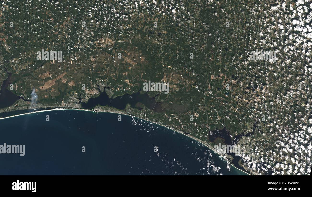 Las arenas blancas de Pensacola Beach se destacan en esta imagen Landsat 9 de la Panhandle de Florida de los Estados Unidos de América, con la Ciudad de Panamá visible bajo algunas nubes de palomitas. Landsat y otros satélites de teleobservación ayudan a rastrear los cambios en las líneas costeras de Estados Unidos, incluyendo el desarrollo urbano y los impactos potenciales del aumento del nivel del mar. Oct 31 2021, el primer día de recolección de datos para Landsat 9. Una versión mejorada de las imágenes originales de Landsat 9. Crédito NASA/USGS Foto de stock