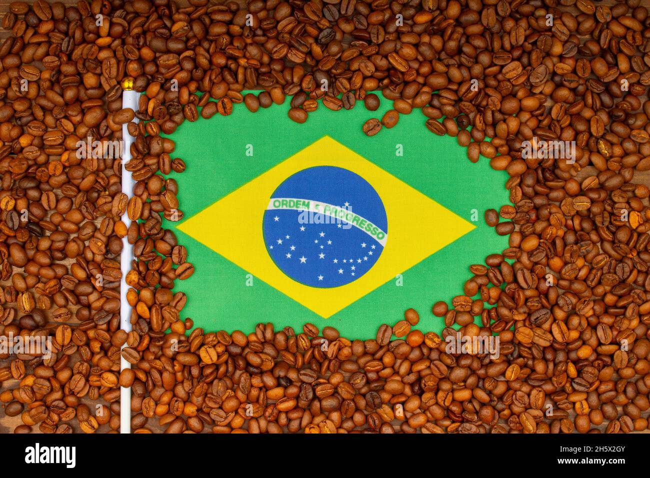 Granos de café tostados y bandera brasileña en la mesa. Concepto de aumento de precios de café brasileño. Los futuros del café arábica suben desde Brasil. Vista superior. Cerrar-u Foto de stock