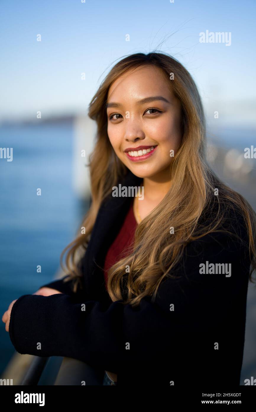 Primer plano retrato de una joven mujer filipina sonriente en el armario de otoño Foto de stock