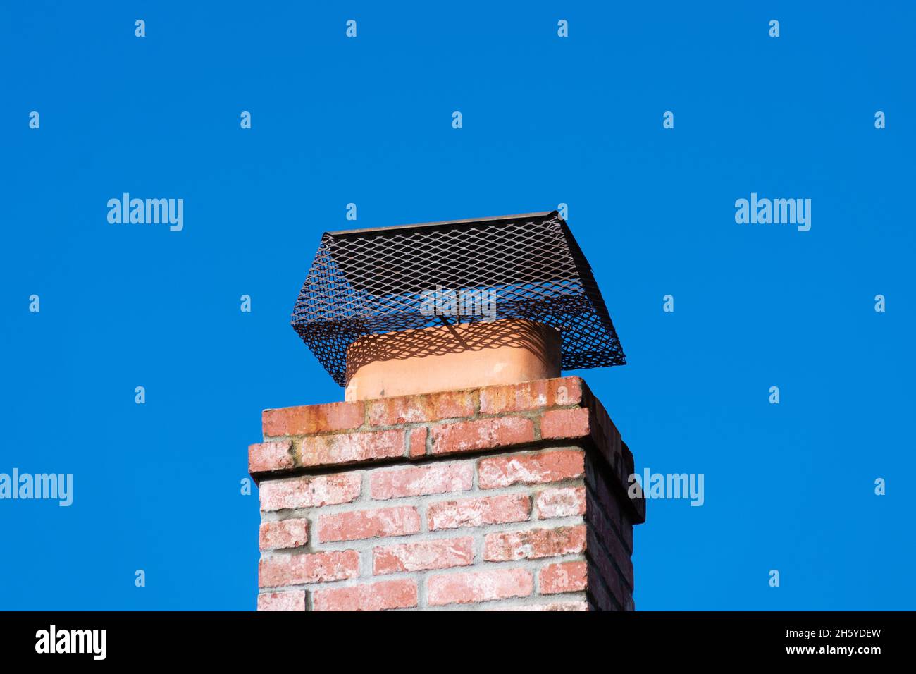 Tapa de chimenea instalada para evitar la entrada de roedores a la casa,  ático, edificio. Chimenea de ladrillo. Cielo azul Fotografía de stock -  Alamy