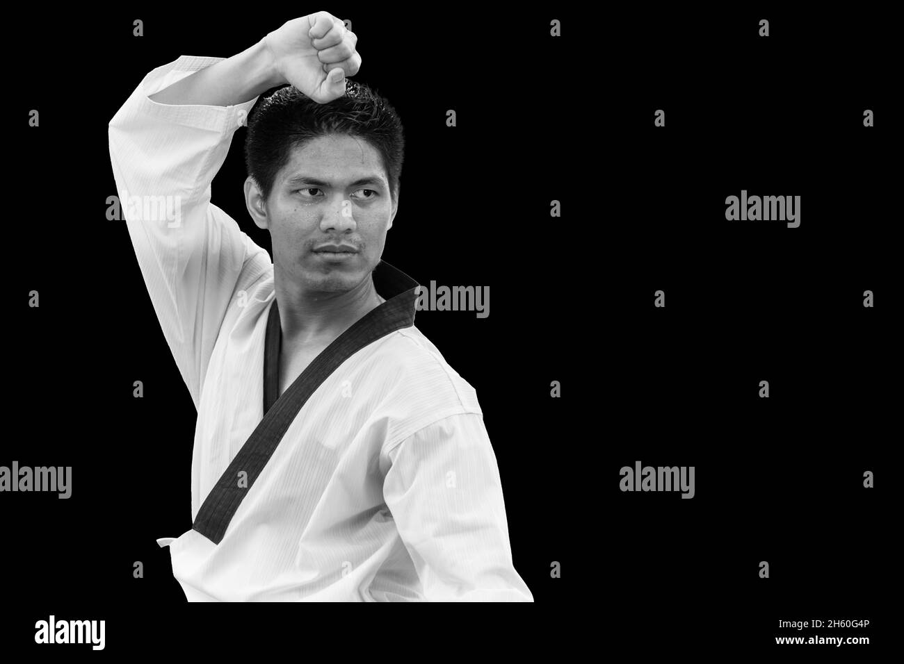 Hombre en el puesto de Tigre con Taekwondo Artes Marciales Asiáticas de auto defensa uniforme aislado en negro Foto de stock