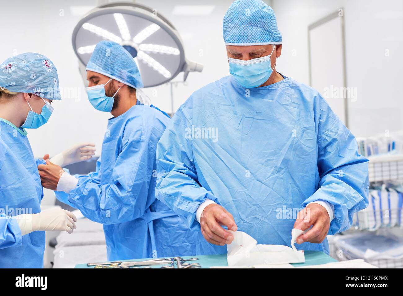 Los médicos se unen en ropa protectora preparando una operación en la clínica de accidentes Foto de stock