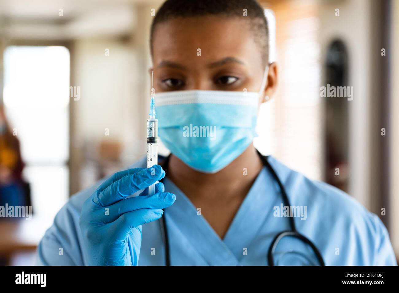 Médico en máscara protectora para la cara que mira la vacuna durante el brote de coronavirus Foto de stock