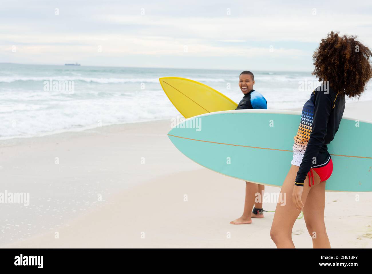 Amigas multirraciales con tablas de surf en la playa durante el fin de semana Foto de stock