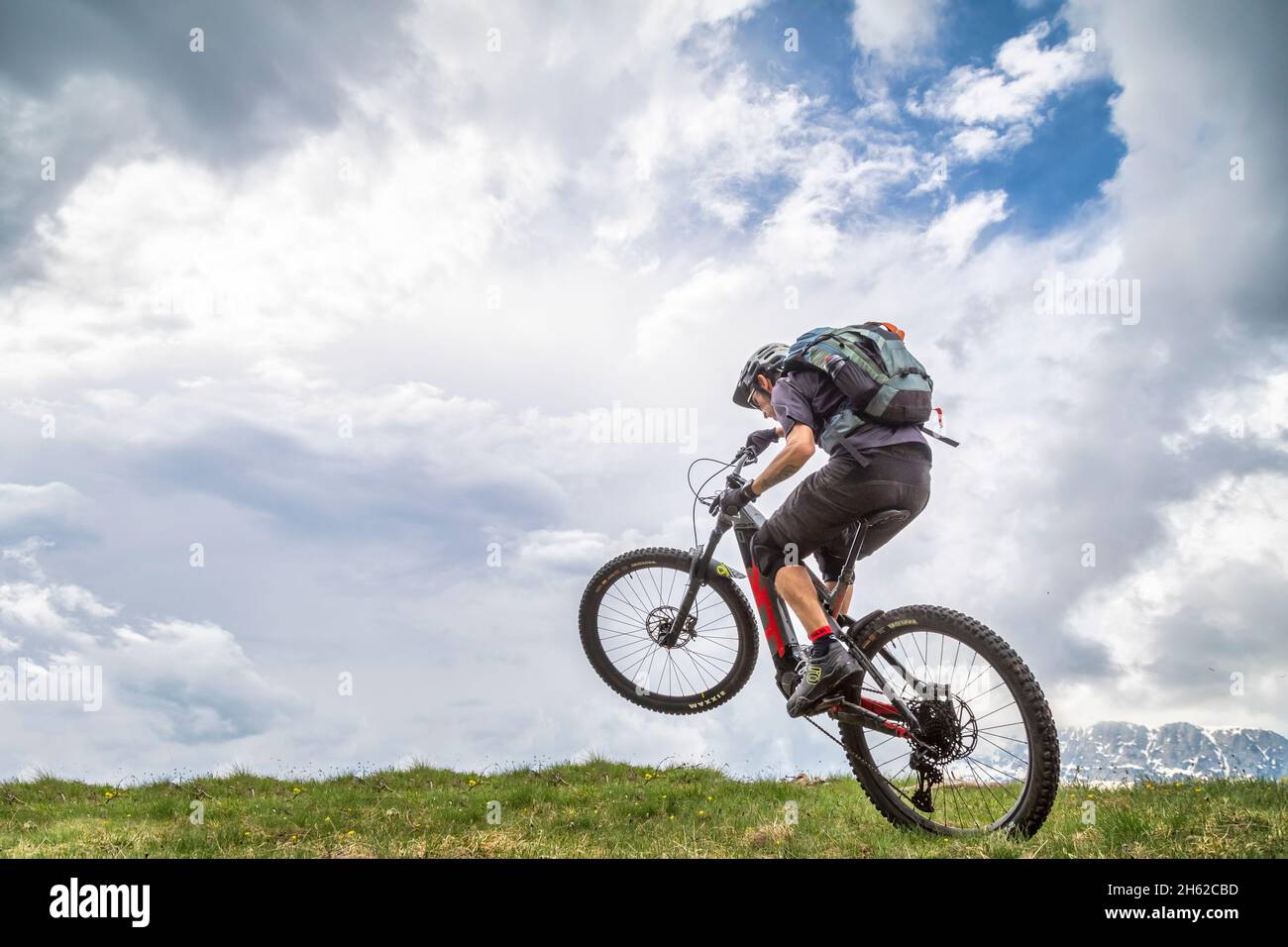 wheelie con e-bike en un campo verde, un hombre de 37 años, dolomitas, belluno, italia Foto de stock