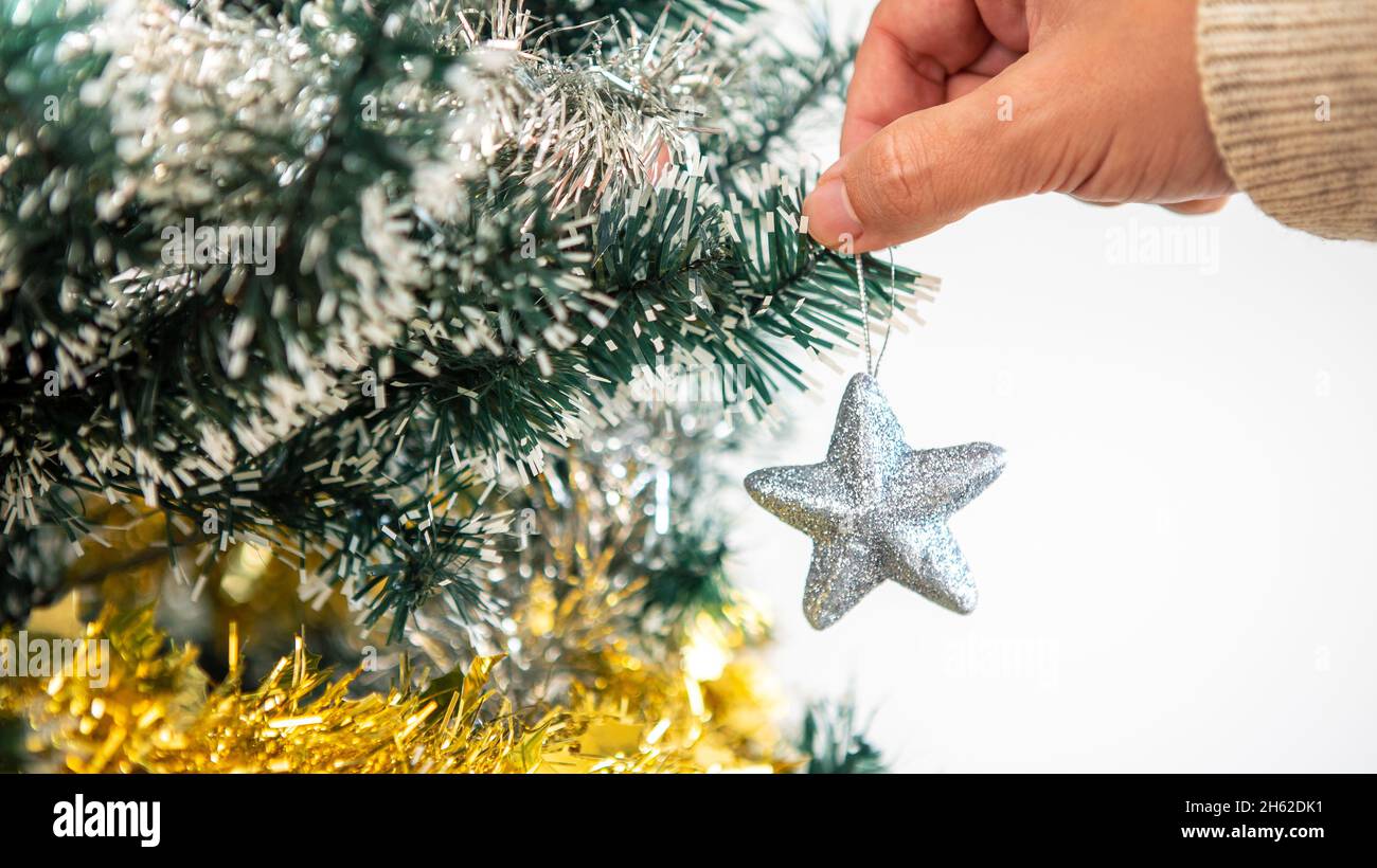 Hombre decorando el árbol de Navidad con estrellas de plata en la casa de  la sala de estar. Feliz Navidad y feliz año nuevo concepto. Gente poniendo  adornos de Navidad en spr