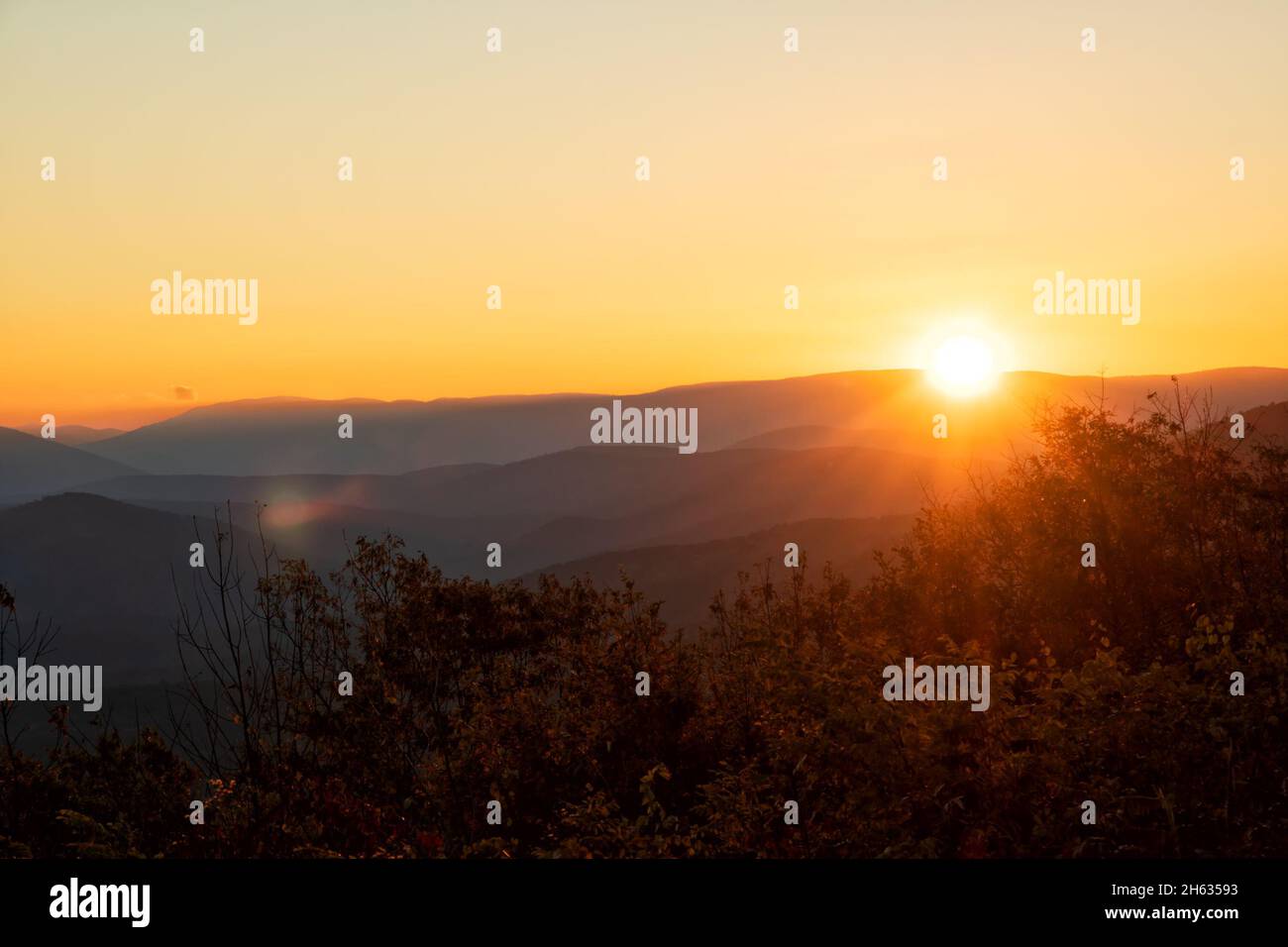 Sol que llega sobre la cima de la montaña a primera hora de la mañana en el bosque nacional de Ouachita; con bengalas y rayos Foto de stock