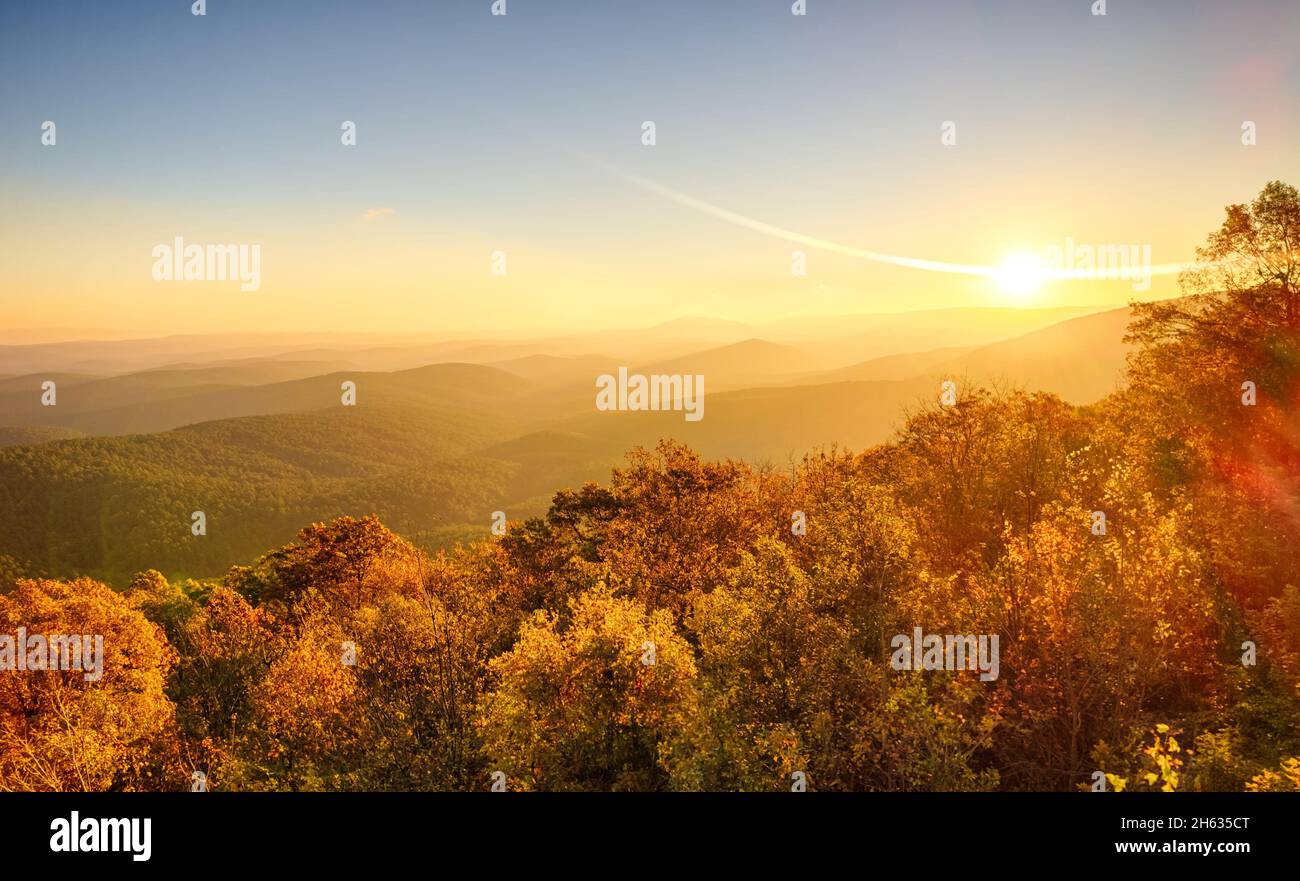 Amanece en noviembre sobre la cima de la montaña en el bosque nacional de Ouachita, con colores otoñales, niebla y niebla en los valles, y bengalas de sol Foto de stock
