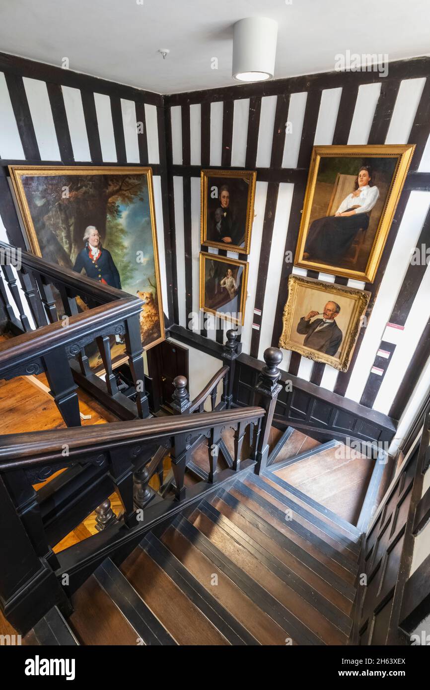 inglaterra, southampton, casa tudor y jardín museo, vista interior que muestra escalera de madera y obras de arte Foto de stock