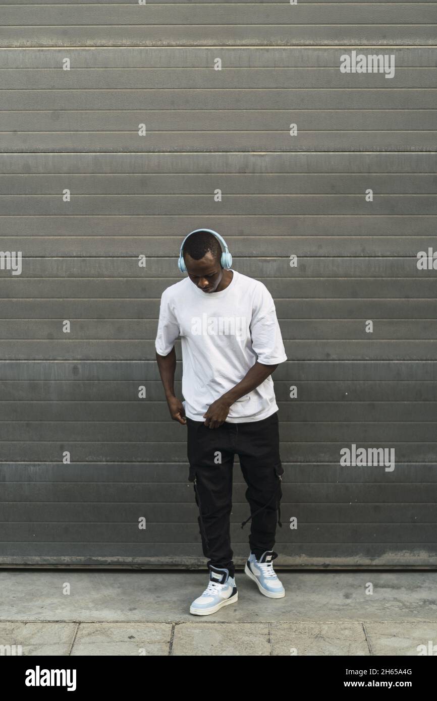 Leche mil millones metálico Toma vertical de un joven hombre negro con un traje de estilo urbano que escucha música con auriculares Fotografía de stock - Alamy Leche mil millones metálico Toma vertical de un joven hombre negro con un traje de estilo urbano que escucha música con auriculares Fotografía de stock - Alamy