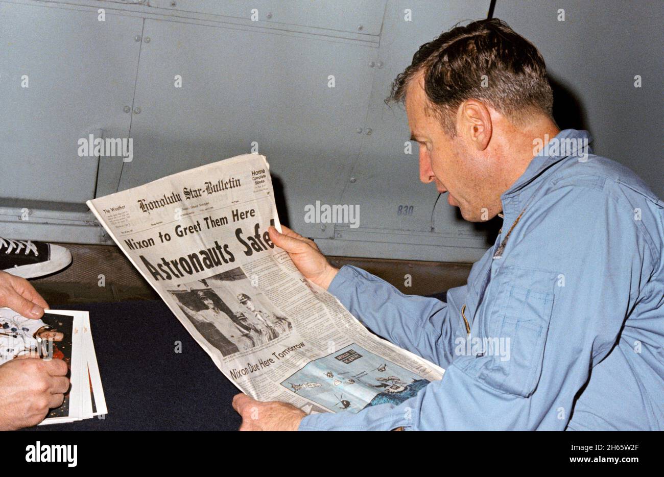 El astronauta James Lovell, comandante de la misión Apolo 13, lee un relato en el periódico sobre la recuperación segura de la misión plagada del problema. Lovell está a bordo del U.S.S. Iwo Jima, buque de recuperación de primera para Apollo 13, Foto de stock