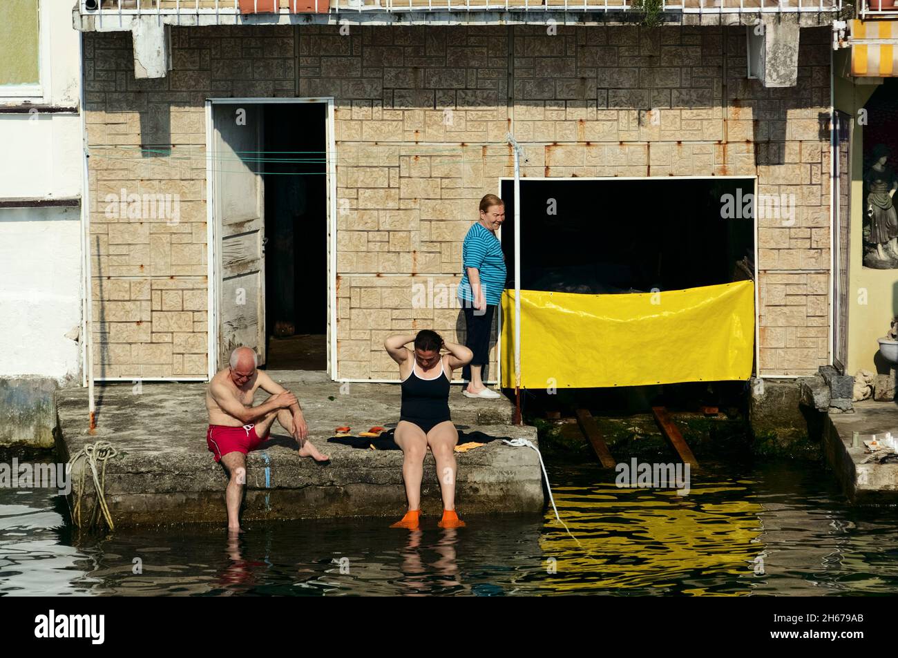 Escena callejera de verano de gente tomando el sol en un pueblo pesquero a orillas del Estrecho del Bósforo, Turquía Foto de stock