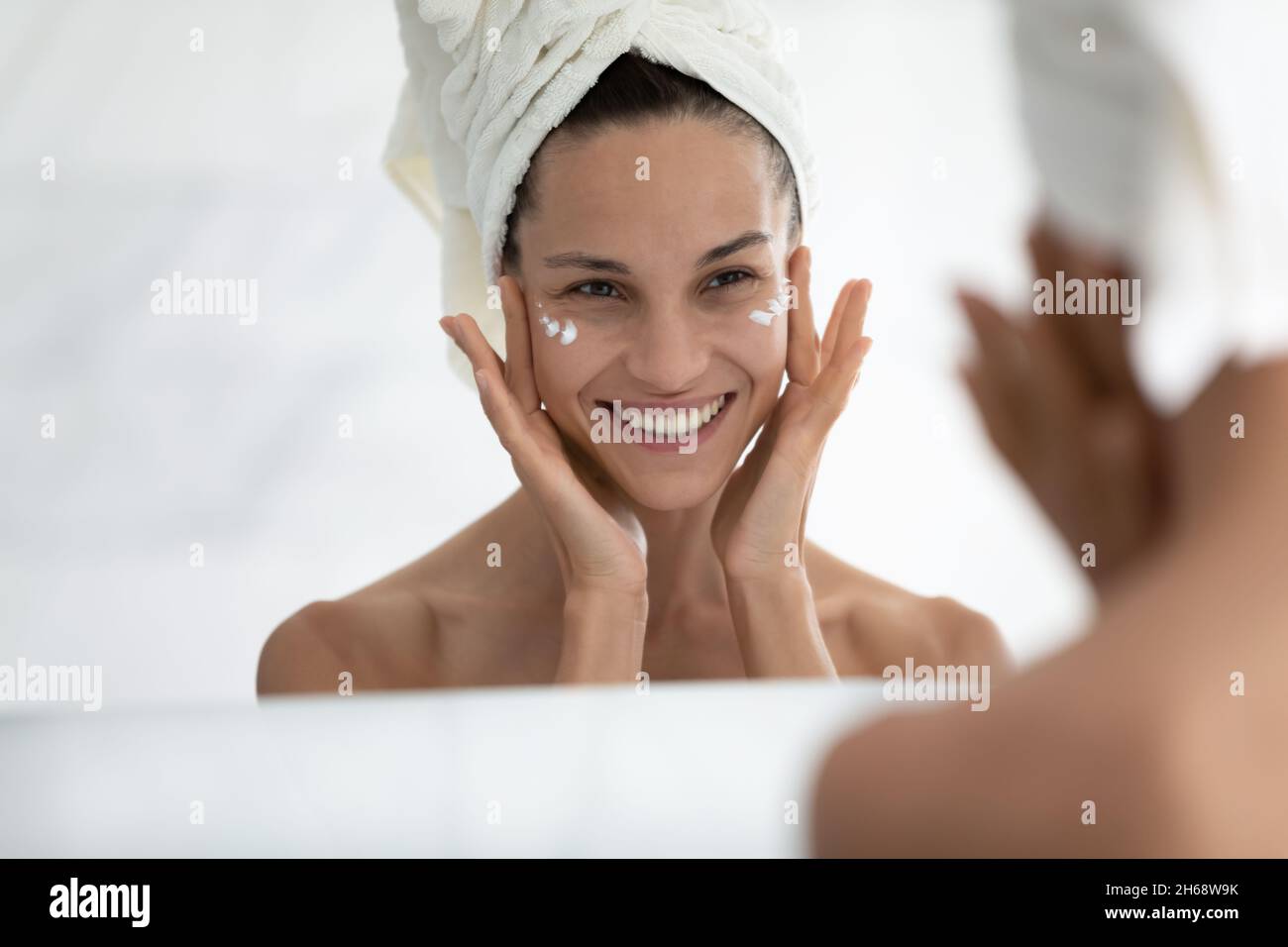 Hombre hispano vestido con maquillaje con gorro de toalla de ducha y  albornoz con una sonrisa feliz y fresca en la cara persona afortunada