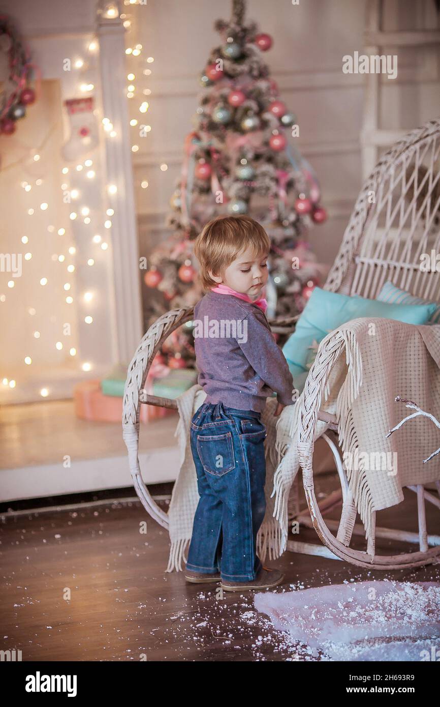 Un niño con corbata rosa está cerca de una silla de ruedas en el fondo de  un árbol de Navidad y una pared decorada con guirnaldas Fotografía de stock  - Alamy