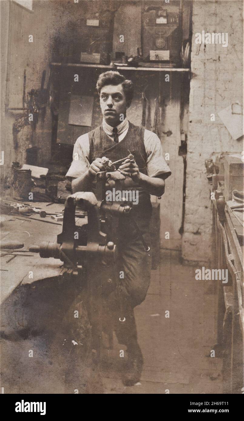 Fotografía de un hombre de aspecto reflexivo de pie en un taller de metalurgia, Londres, 1907 Foto de stock