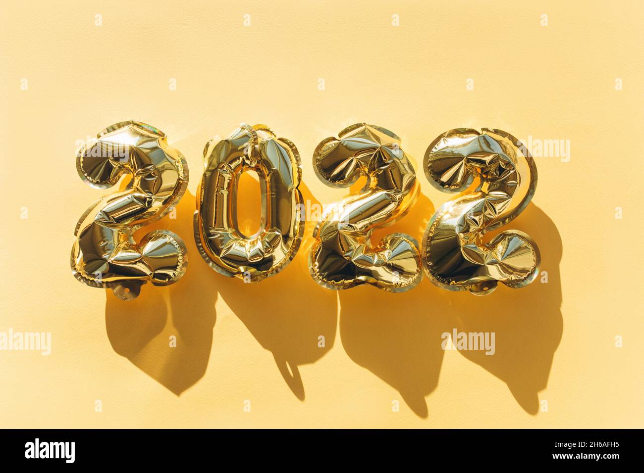 Globos hechos de papel de aluminio dorado con los números 2022 sobre fondo dorado. Celebración de Navidad, Año Nuevo y el concepto de vacaciones. Plano, vista superior. Foto de stock
