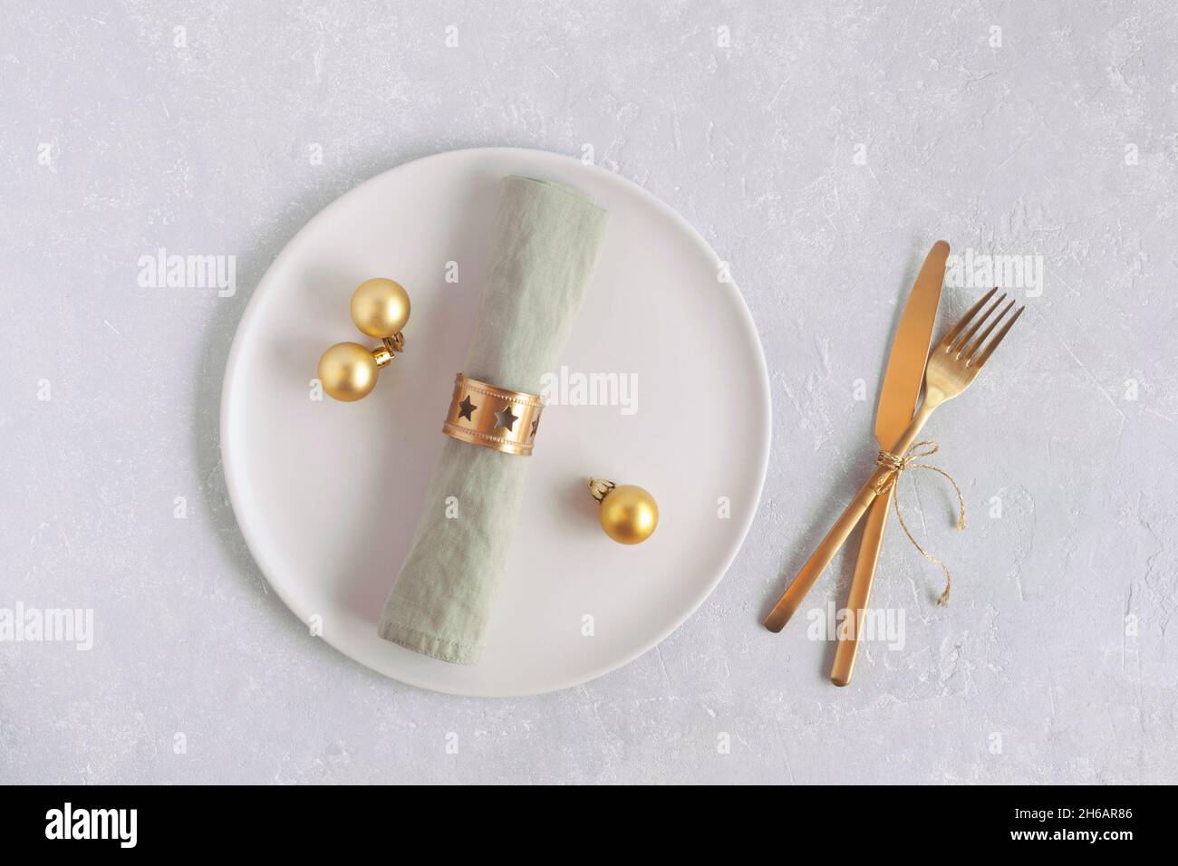 plato y cubiertos para la cena de año nuevo, vista de arriba, colores dorados, sobre fondo gris Foto de stock