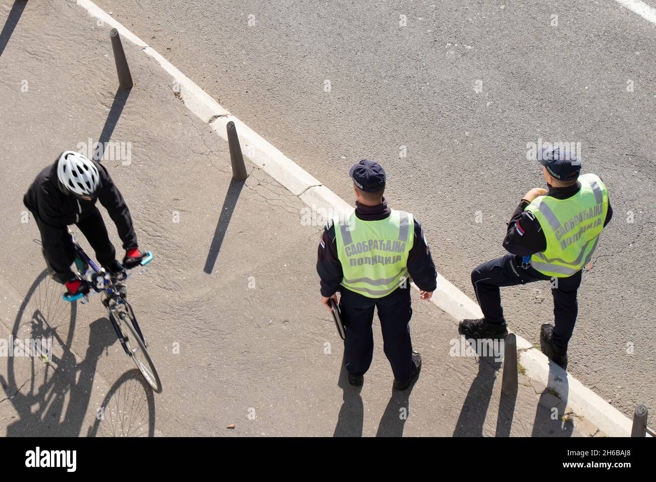 Belgrado, Serbia - 25 de octubre de 2021: Dos policías de tráfico de guardia en la calle de la ciudad y un ciclista en movimiento desenfoque, vista trasera de ángulo alto Foto de stock