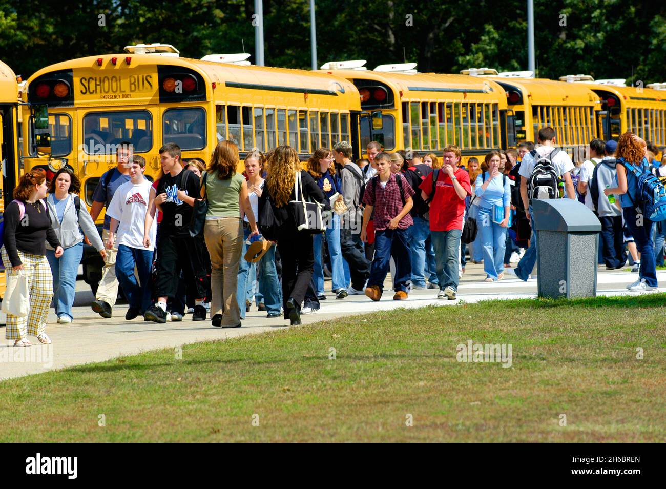 Los estudiantes de secundaria de salida al final del día para andar en buses escolares para el transporte home Foto de stock