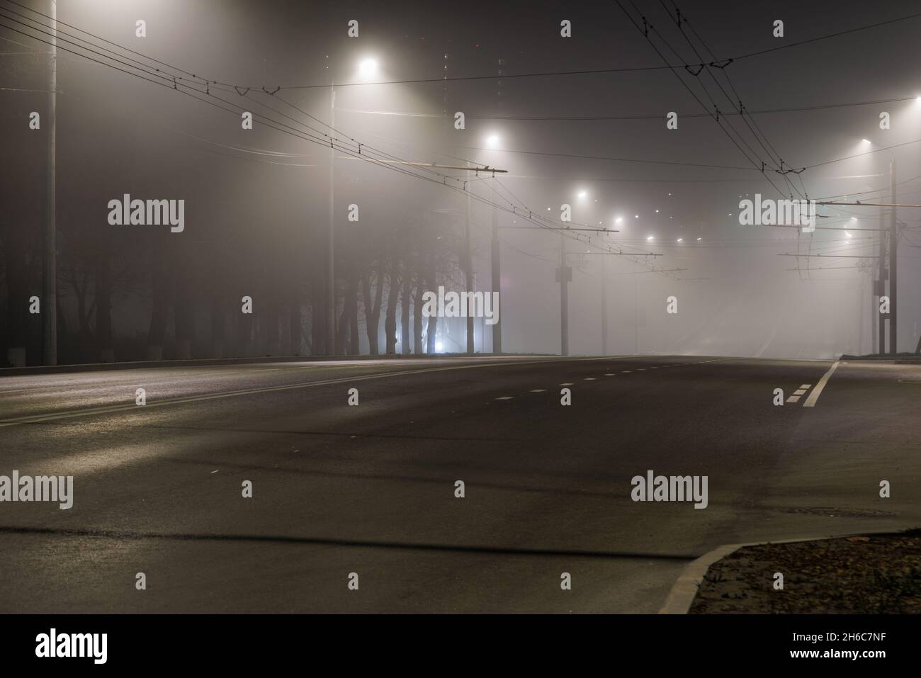 camino nocturno vacio con filas de postes de lámparas Foto de stock