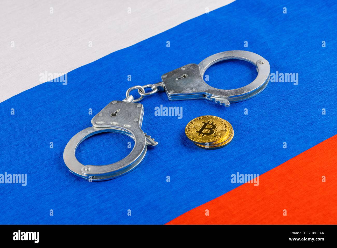 rollo de papel ruso rublos moneda y moneda de bitcoin shiner encadenado con esposas en el fondo de la bandera rusa Foto de stock