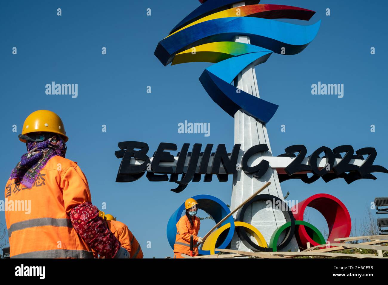 Los trabajadores ecológicos urbanos trabajan frente a un enorme emblema de los Juegos Olímpicos de Invierno de Beijing 2022 en Beijing, China. 14-Nov-2021 Foto de stock