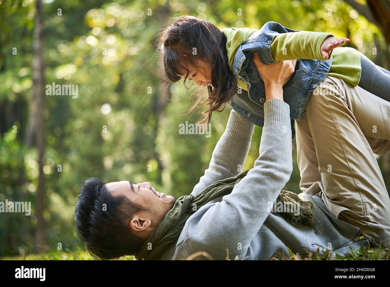padre asiático y su hija divertirse al aire libre en la hierba en el parque de la ciudad Foto de stock