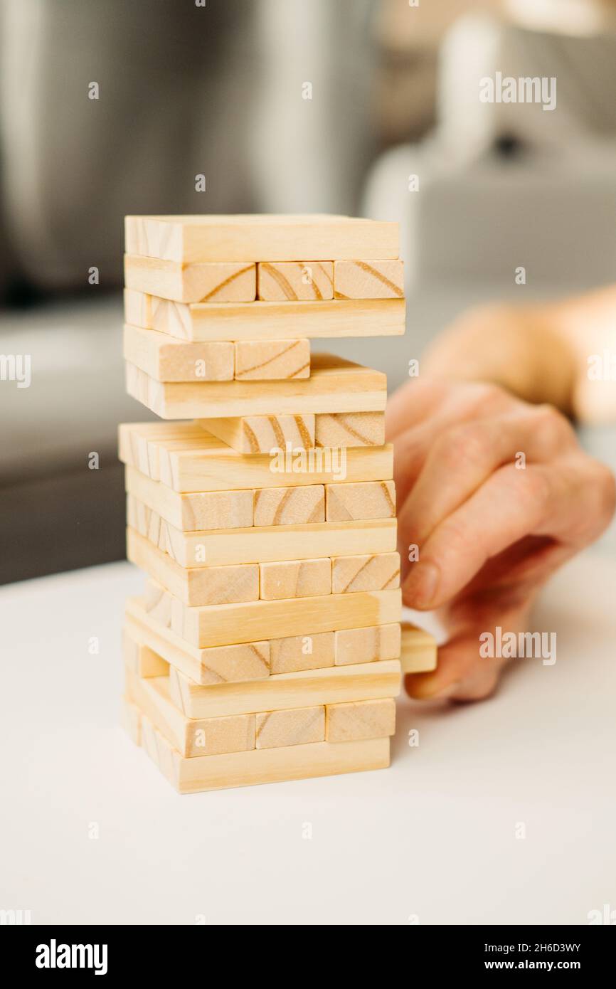 El primer plano de las manos del niño, en una camiseta blanca juega en  casa, en la mesa de Jenga. Juegos de mesa para niños y adultos. Un  pasatiempo sin gadgets. Juegos