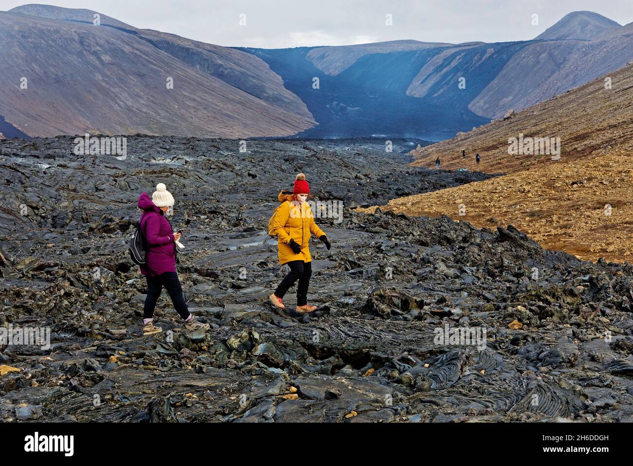 Dos turistas caminan sobre el flujo de lava fría, Islandia, la península de Reykjanes, Fagradalsfjall Foto de stock