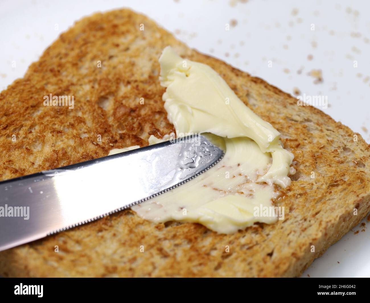 primer plano de la cuchilla que extiende la magarina sobre la tostada integral Foto de stock