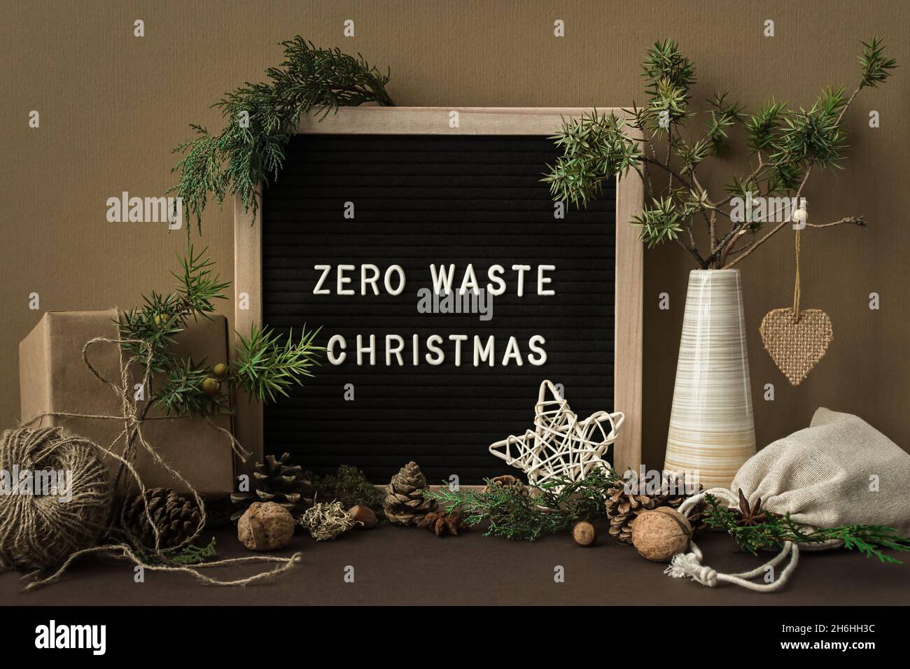 Concepto de Navidad sin residuos. Materiales naturales, madera, papel, embalaje, ramas de abeto conos tuercas. Marco con inscripción. Tarjeta de felicitación en estilo ecológico Foto de stock