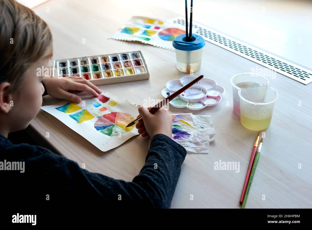 Niños pintando cuadros con pinturas de acuarela durante la lección