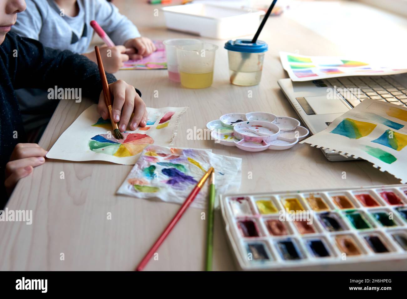 Niños pintando cuadros con pinturas de acuarela durante la lección