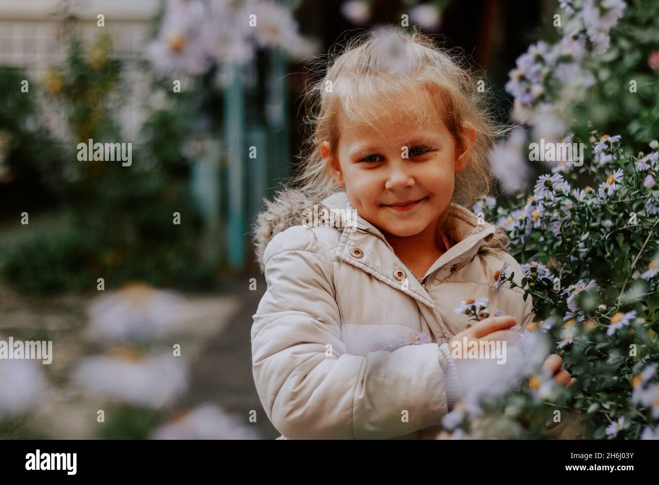 Retrato de un niño de 4 años al aire libre. Chica linda y flores. Bebé en  una chaqueta blanca en el otoño. Infancia Fotografía de stock - Alamy