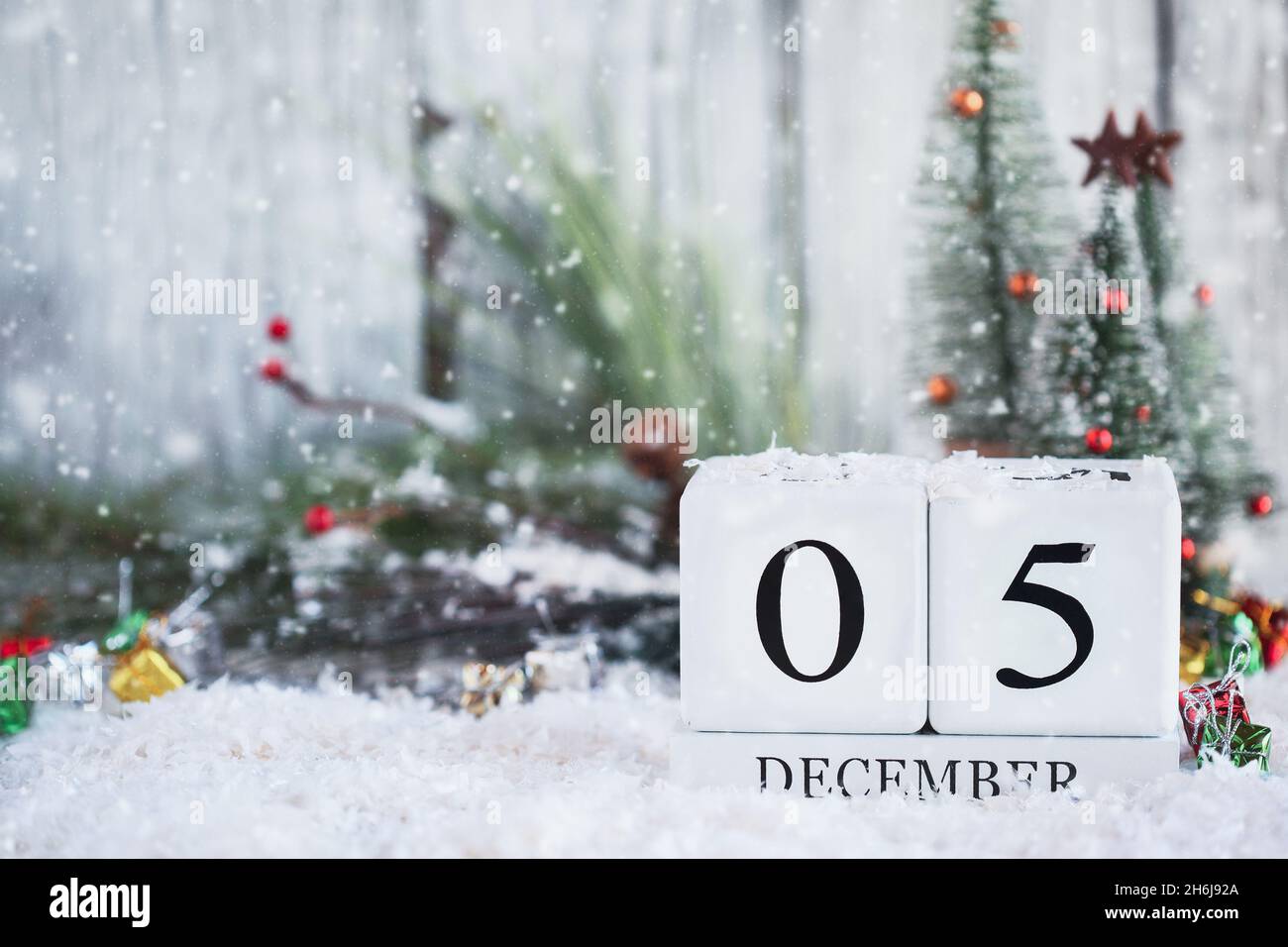 Bloques de calendario de madera blanca con la fecha 5th de diciembre y decoraciones navideñas con nieve. Enfoque selectivo con fondo borroso. Foto de stock