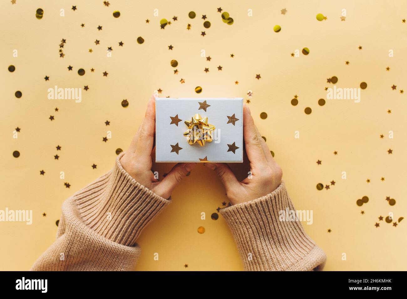 La chica sostiene una caja con un regalo en sus manos. Números cercanos de confeti y oro y plata 2022. Fondo festivo de Año Nuevo y concepto de Navidad. Foto de stock