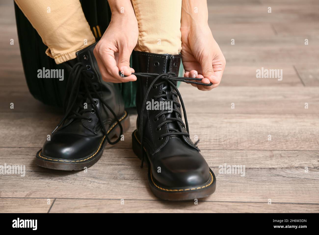 Mujer con botas negras que ata los cordones de las zapatillas en casa,  primer plano Fotografía de stock - Alamy