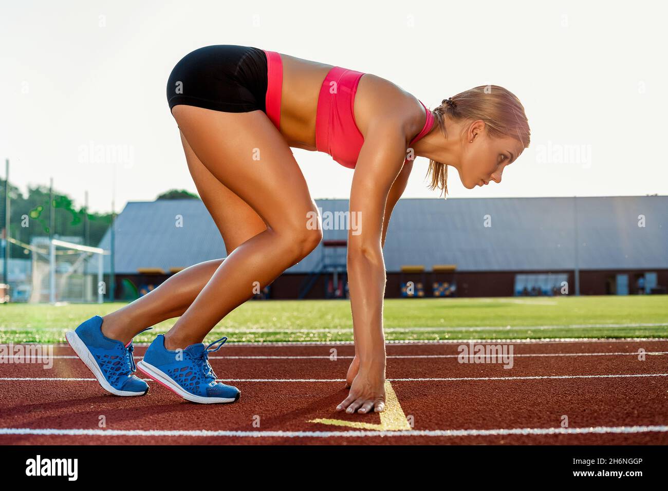 Mujer joven atleta en posición de inicio listo para comenzar una carrera en  pista Fotografía de stock - Alamy