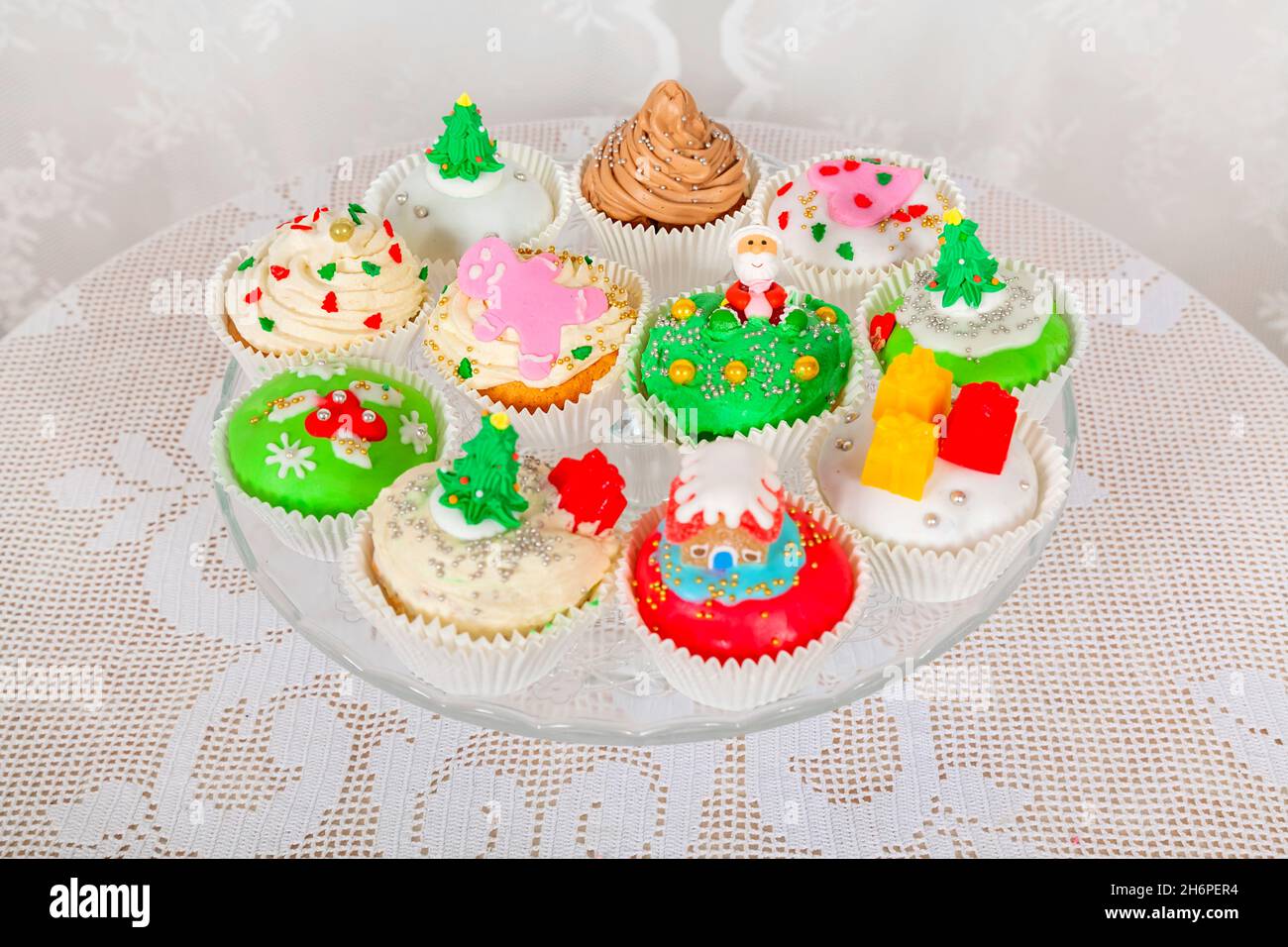 Un soporte de cristal con pasteles caseros, pastelitos, magdalenas decoradas en un estilo navideño. Mini pastelitos de postre navideños festivos de temporada en d tradicional Foto de stock