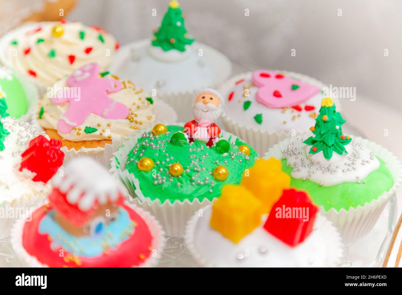 Pasteles caseros, pastelitos, magdalenas decoradas en un estilo navideño. Mini cupcakes de postre navideños festivos de temporada con símbolos decorativos tradicionales e Foto de stock