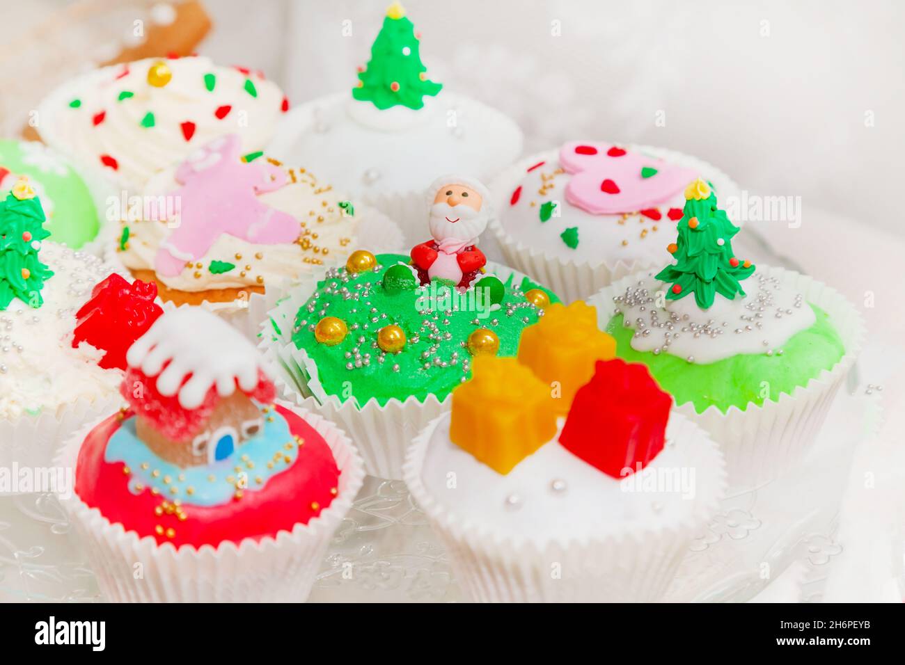 Pasteles caseros, pastelitos, magdalenas decoradas en un estilo navideño. Mini cupcakes de postre navideños festivos de temporada con símbolos decorativos tradicionales e Foto de stock