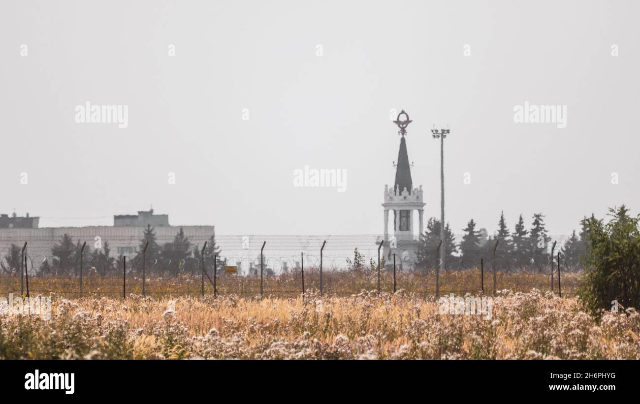Protección del territorio del aeropuerto internacional cerca de seguridad y edificio con torre en pradera con cielo gris. Kharkiv, Ucrania en verano Foto de stock