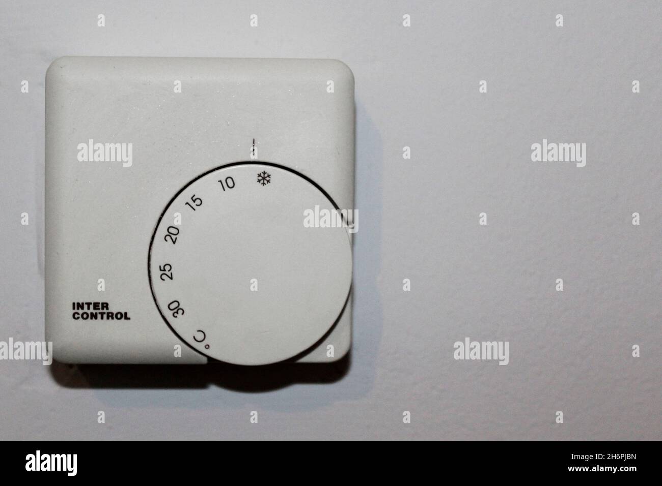 Weißer Termostato zur Wärmeregulierung von 0 bis 30 Grad einstellbar, en einer Wohnung an einer Wand, komplett abgestellt. Foto de stock