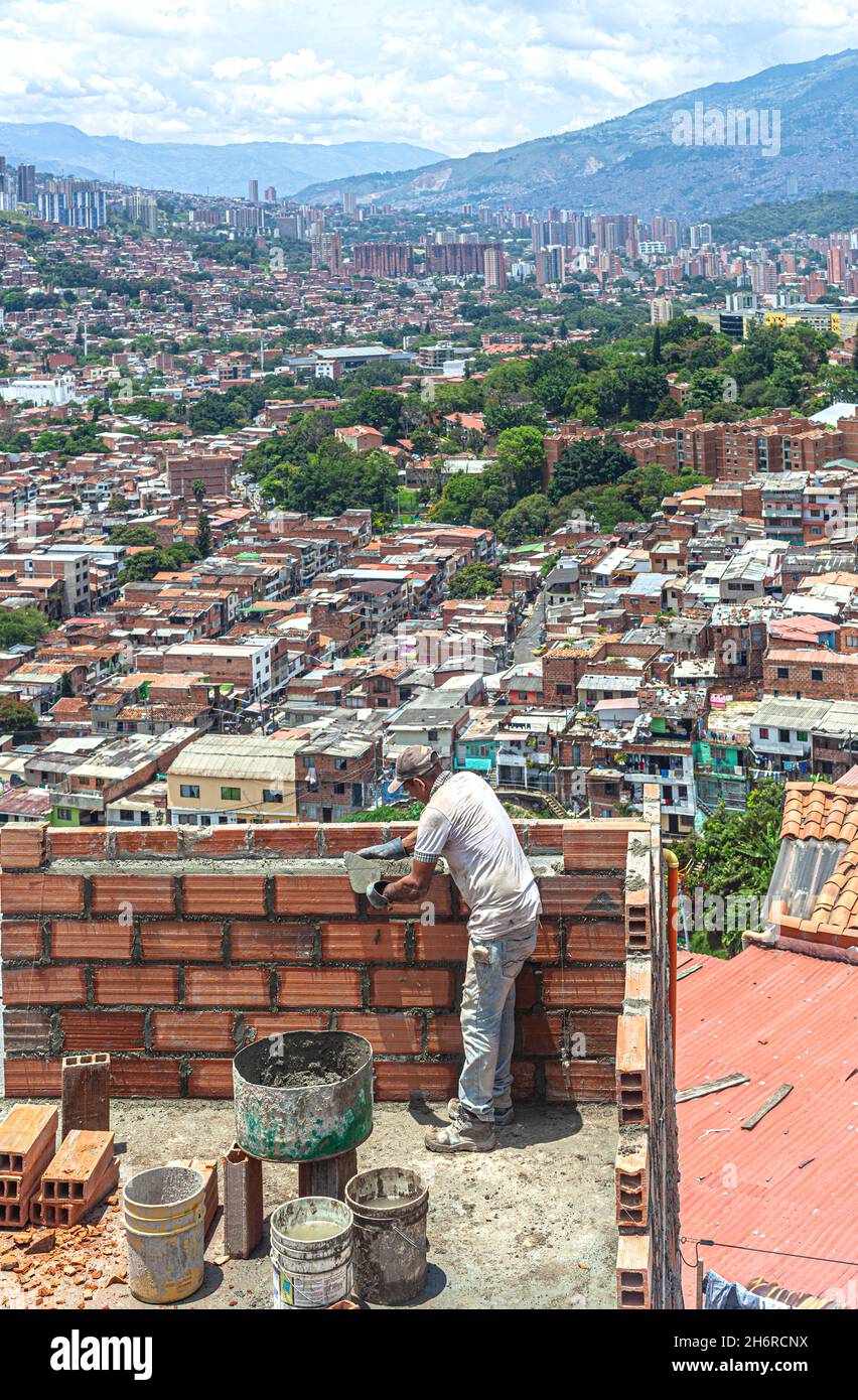 Bricklayer en el trabajo en la parte superior de una casa con vistas a la ciudad, Comuna 13, Medellín, Colombia. Foto de stock